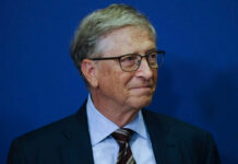 A business leader with glasses smiling in front of a blue background