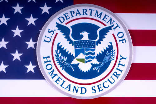 London,,Uk,-,March,18th,2018:,The,Symbol,Of,The U.S. Department of Homeland Security emblem on a background of the American flag