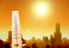 A thermometer held against a sunset city skyline