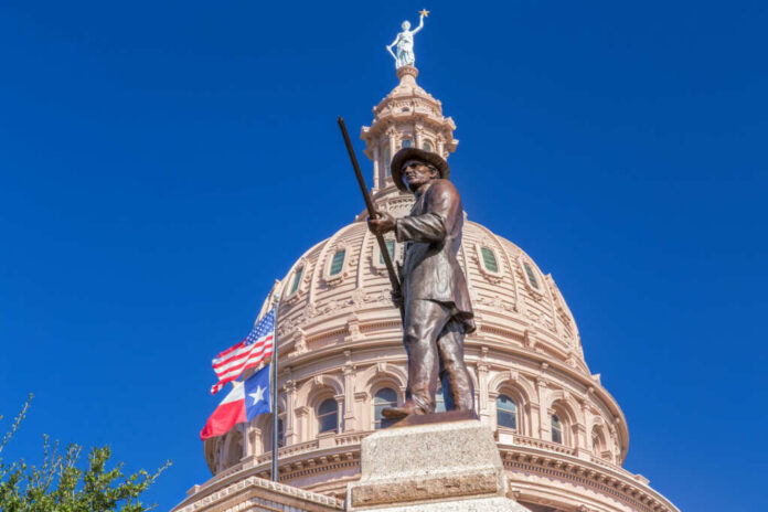 Bronze statue in front of the Texas State Capitol building under a clear blue sky