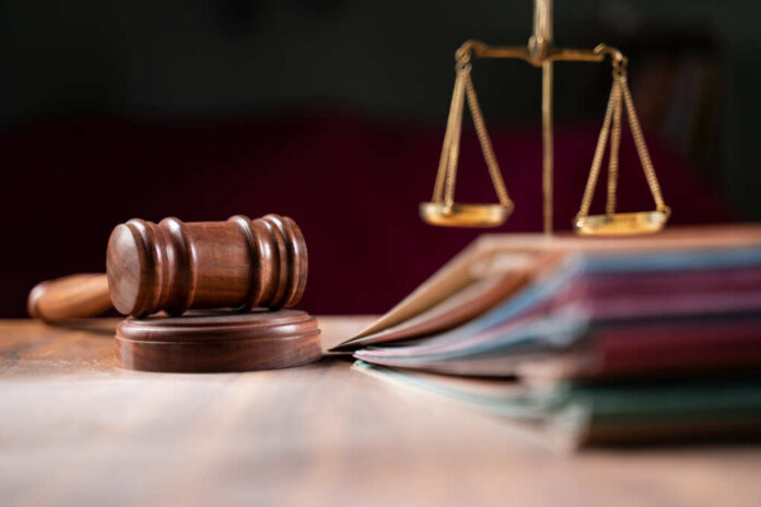 A wooden gavel and scales of justice on a table with law books
