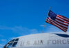 Aging Bomber, Eight Dead — What Failed? Close-up of a U.S. Air Force aircraft with an American flag waving against a blue sky