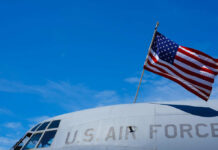 Aging Bomber, Eight Dead — What Failed? Close-up of a U.S. Air Force aircraft with an American flag waving against a blue sky