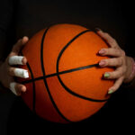 LSU Outrage Triggers Sudden LA Times Flip Hands with bandages holding an orange basketball against a dark background