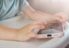 Childs hands interacting with a tablet on a table