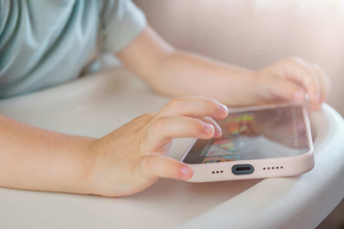Childs hands interacting with a tablet on a table
