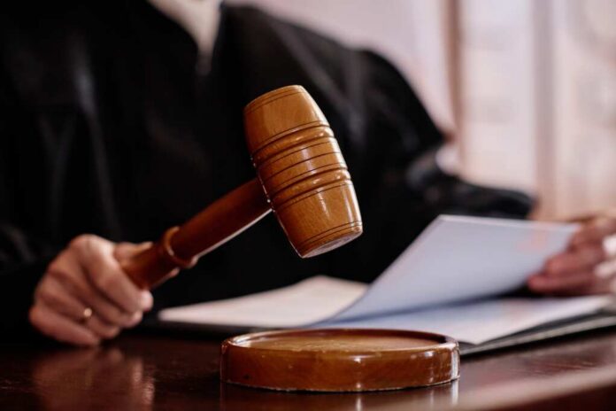 Wooden,Gavel,Held,By,Experienced,Female,Judge,Over,Sounding,Block A judges gavel poised above a wooden block with a document in the background