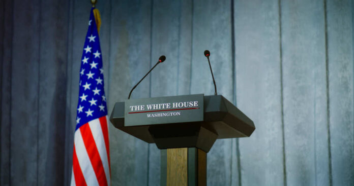shutterstock_2448402565 Press podium with microphones and American flag in the background