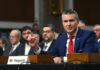 Fog Of War—Deadly Hits, Unanswered Questions A man in a blue suit speaking at a senate hearing with a panel of officials behind him