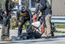 Police officers apprehending a suspect on the ground