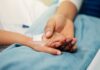 Missed Warnings, Sudden Collapse A patient holding hands with a loved one in a hospital setting