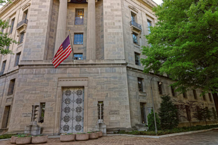 shutterstock_466879760-1 Exterior view of a government building featuring the American flag and decorative entrance