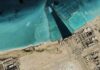 Water War Flashpoint—Gulf on Edge Satellite view of coastal industrial complex with seawater inlet and turquoise shallows