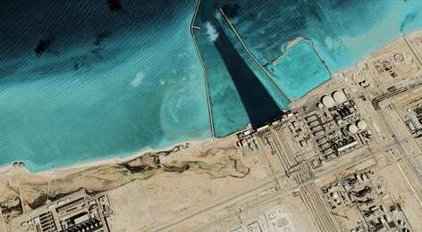 2523824585 Satellite view of coastal industrial complex with seawater inlet and turquoise shallows