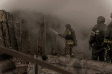 Firefighters spray water into a smoke-filled structure