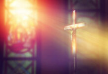 Cardinal’s Memorial Sparks Theological Firestorm A crucifix illuminated by soft light in a church setting