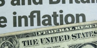 Close-up of a US dollar bill with a newspaper headline about inflation