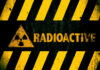 Radioactive warning sign with yellow stripes and a caution symbol
