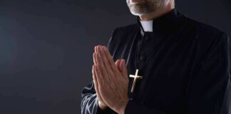Clergyman in black robe praying with hands together