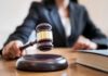 A judges gavel poised above a wooden block on a desk