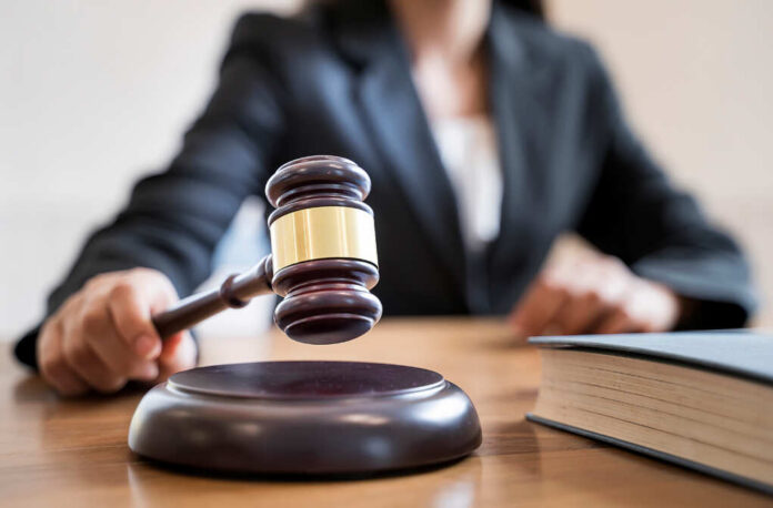Woman,Judge,Hand,Holding,Gavel,To,Bang,On,Sounding,Block A judges gavel poised above a wooden block on a desk