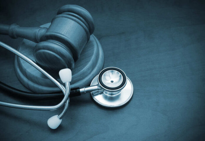 shutterstock_1358884013 A wooden gavel next to a stethoscope on a dark surface