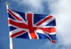 Staggering Surge Slams UK Border British flag waving against a blue sky