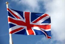 Staggering Surge Slams UK Border British flag waving against a blue sky