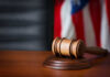 Buried Letter Reignites Church-State Brawl A wooden gavel resting on a round base with a blurred American flag in the background