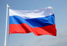 OSCE Probe Targets Russia’s Kid Pipeline Russian flag waving against a clear blue sky