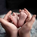 Italy’s Baby Bust Hits 80-Year Low adult hands cradling newborn baby feet