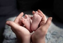 Italy’s Baby Bust Hits 80-Year Low adult hands cradling newborn baby feet