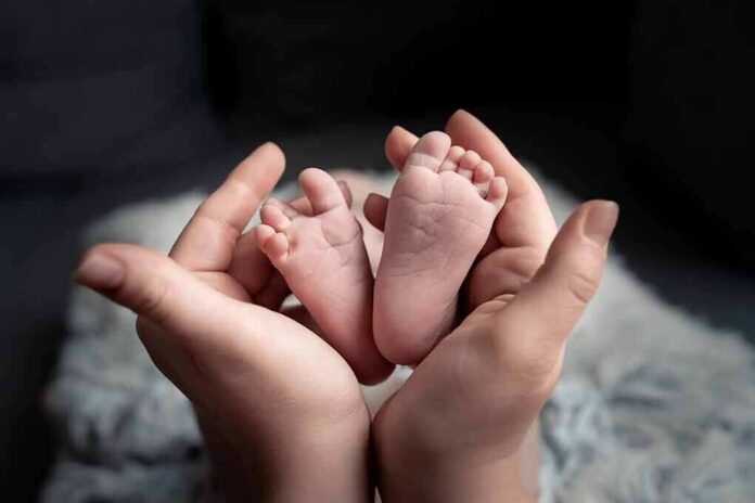 shutterstock_2109999725 adult hands cradling newborn baby feet