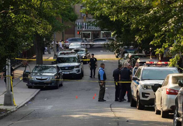 shutterstock_2330301305-1 Police officers secure a residential street with patrol cars and yellow tape