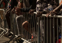 July 4 Flashpoint: Teen Takeovers Loom Close-up of hands resting on a barrier in a crowded urban setting