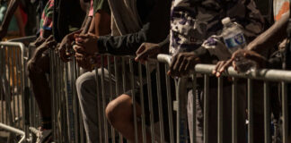 Close-up of hands resting on a barrier in a crowded urban setting