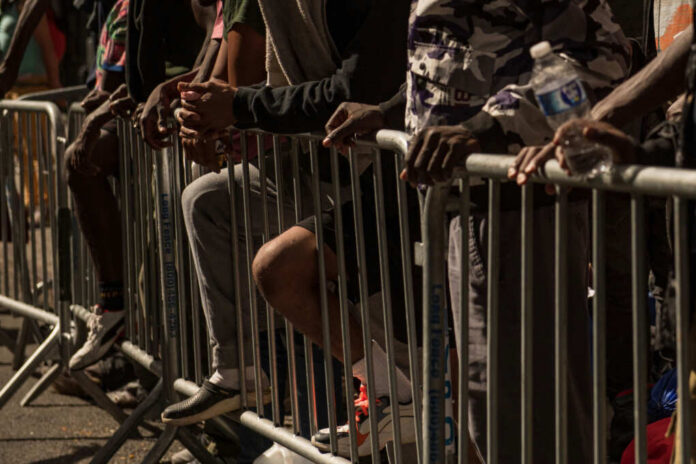shutterstock_2346840027 Close-up of hands resting on a barrier in a crowded urban setting