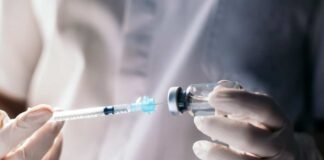 A healthcare professional preparing a syringe from a vial