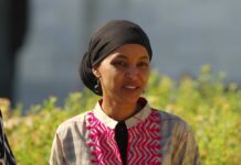 Transparency Brawl Engulfs Ilhan Omar A woman in traditional attire smiling outdoors with greenery in the background