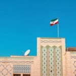 Backchannel Bombshell: U.S. Flags Assassination Risk Building with intricate patterns and the Iranian flag against a clear blue sky