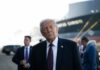BILLION-Dollar Crypto Flood Hits White House A political figure in a suit looking thoughtfully at an outdoor event with a ship in the background