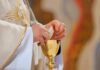 Communion Controversy Erupts at Papal Liturgy Priest holding a communion wafer over a gold chalice