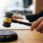 Judge Tosses Harvard Antisemitism Case Judge's hand holding a gavel over a sound block