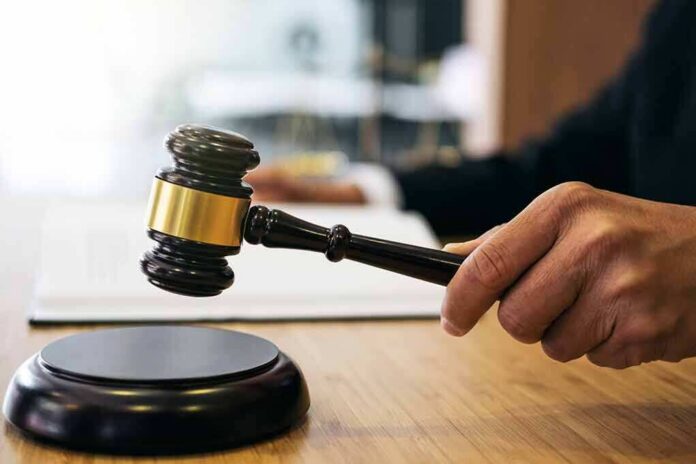 shutterstock_1023698749 Judge's hand holding a gavel over a sound block