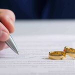 Caregiver Dating Bombshell Sparks Fury Hand signing a document beside two gold wedding rings