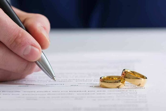 shutterstock_1043592691-1 Hand signing a document beside two gold wedding rings