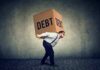 Man carrying a large box labeled debt on his back
