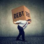Trillion-Dollar War Binge Sparks Debt Jitters Man carrying a large box labeled debt on his back