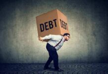 Trillion-Dollar War Binge Sparks Debt Jitters Man carrying a large box labeled debt on his back