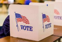 Vouching Rule Ignites Election Integrity Fight voting booth with American flag graphics